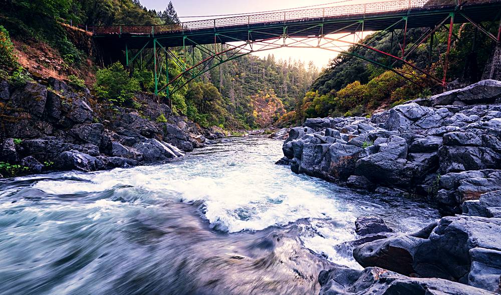 The Highway 49 bridge over the South Yuba River at dusk, whitewater running over granite beneath it.
